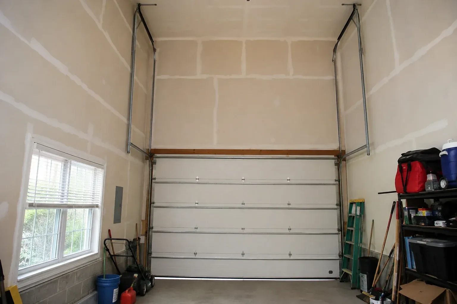 Tall garage interior with a sectional door and tracks extending into overhead space. — High-Lift Garage Door Conversion, Georgina